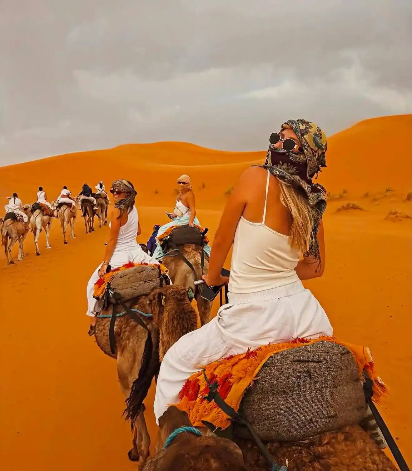 Traveller riding a camel through the orange dunes of Erg Chebbi on a 6-day desert tour from Tangier